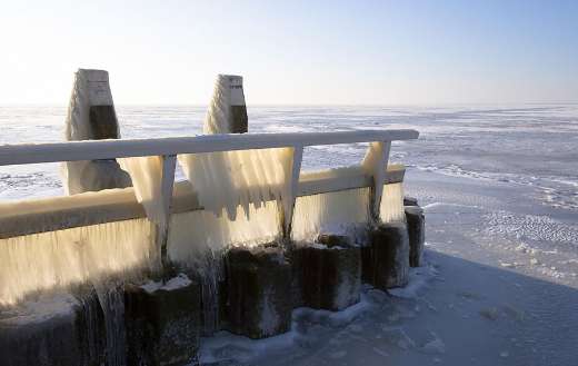 Icicles hang from a pier over frozen water