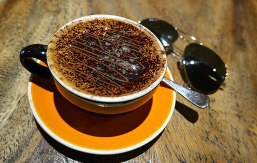 Delicious cup of coffee sprinkles with chocolate powder
