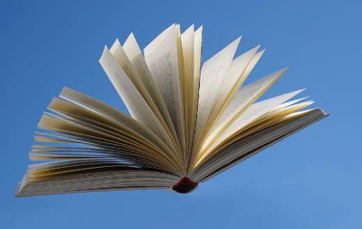 Open book floating against clear blue sky