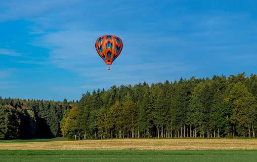 A colorful hot air balloon flying over a forest